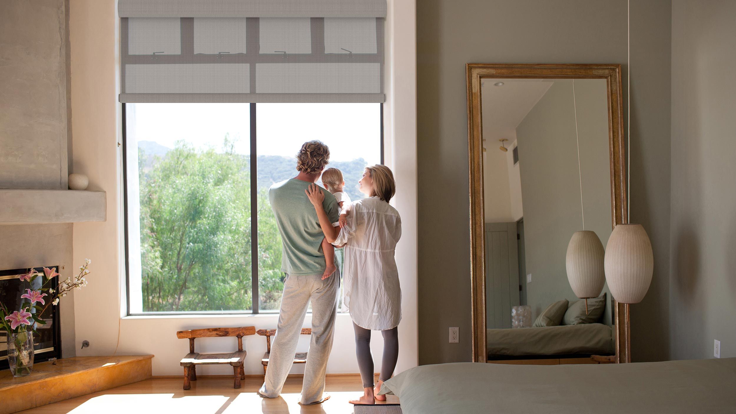 Couple with a baby in a bedroom with Crestron roller shades